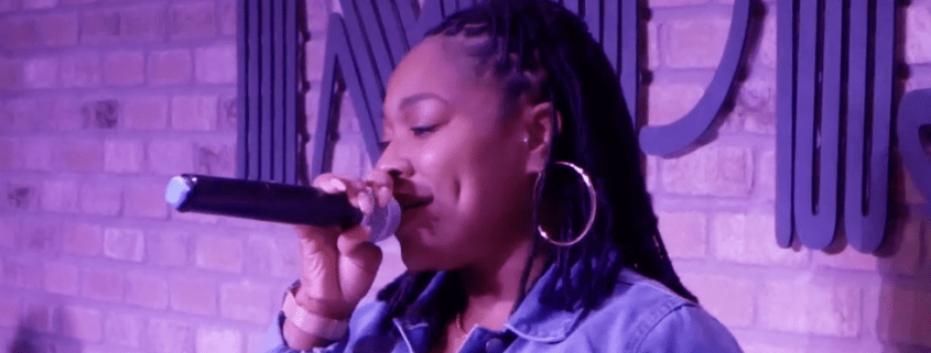 Woman singing into microphone on stage.